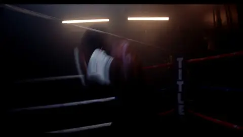 Third-pass frame candidate. Source-level review: Dramatic boxing silhouettes and ring atmosphere, but many frames are very dark, motion-heavy, or face/athlete dependent. Individual frame still requires close visual review unless source-level decision is reject.