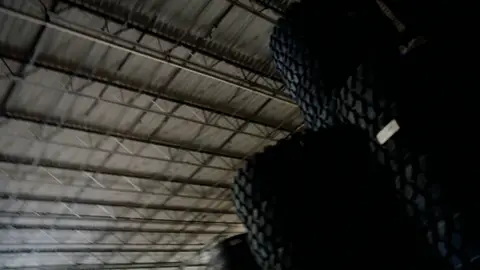Third-pass frame candidate. Source-level review: Strong warehouse/tire/forklift material with better subject clarity than earlier passes. The orange fast-pan smear and obstructed worker frames are explicitly excluded. Individual frame still requires close visual review unless source-level decision is reject.