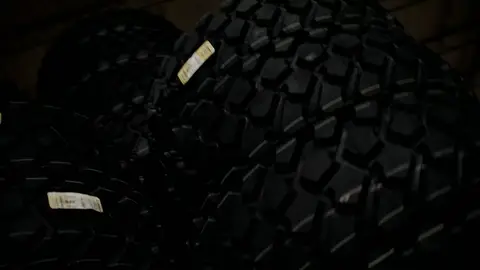 Third-pass frame candidate. Source-level review: Strong warehouse/tire/forklift material with better subject clarity than earlier passes. The orange fast-pan smear and obstructed worker frames are explicitly excluded. Individual frame still requires close visual review unless source-level decision is reject.