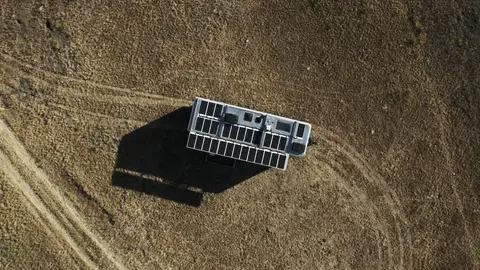 Strong overhead field composition with trailer shadow and solar roof readable.