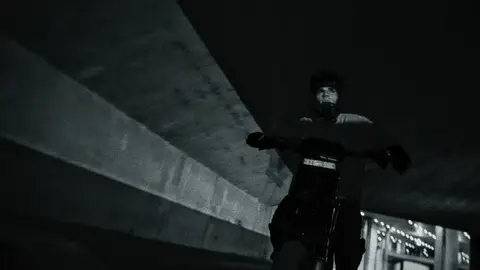 Strong black-and-white rider moment with dark underpass atmosphere.