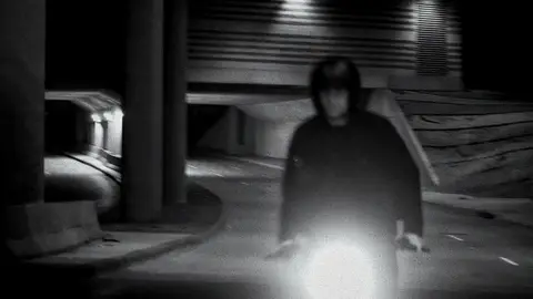 Night rider/headlight frame has energy but remains very dark.