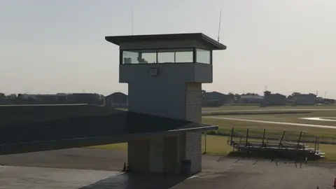 Clean control-tower establishing frame with useful racetrack architecture, but limited action.