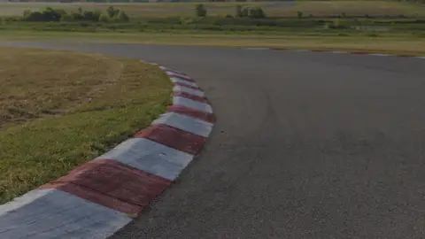 Strong wide racetrack curve with clean red-and-white curb geometry.