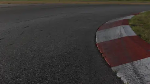 Strong low curb detail with asphalt texture and a clear racing-line visual idea.