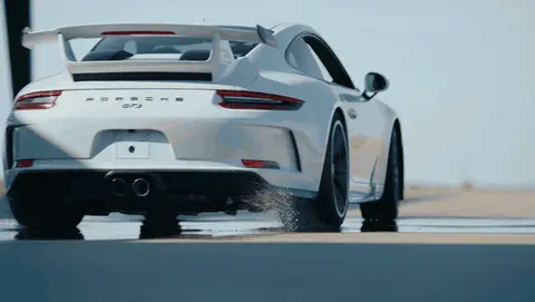 Strong rear Porsche acceleration beat with spray and clear vehicle movement.