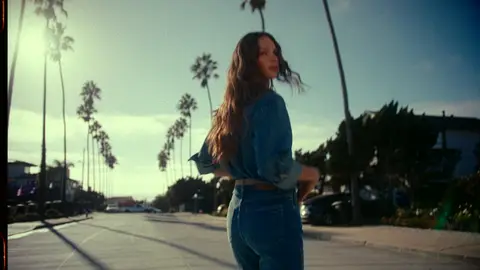 Strong street fashion hero with clear model, movement, palm-lined environment, and clean negative space.