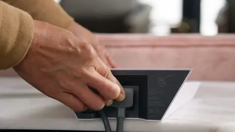 Strong hand-and-router cable connection detail showing product setup action.