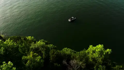 Strong aerial lake/boat context with clean green shoreline and clear scale.