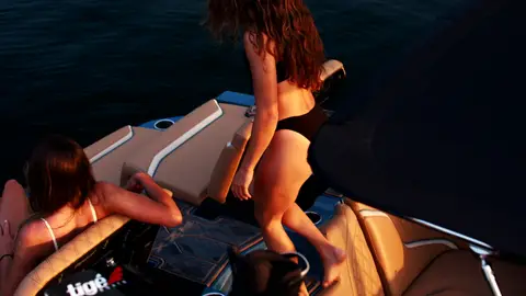 Useful onboard lifestyle angle with people and boat seating, but faces/body/release review is required.