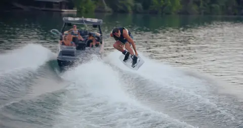 Useful wake/boat context with rider, but the subject is distant and softer.
