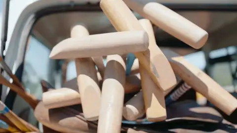 Several cylindrical wooden polo mallet heads overlap in a close-up showing their grain, worn edges and shafts.