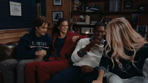 Four adults lean and settle together on a leather sofa in a decorated holiday room.
