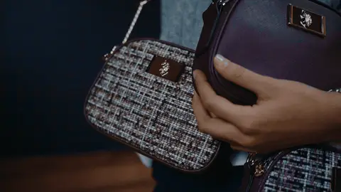 The camera moves across burgundy and tweed crossbody bags, a hand and gold-tone chain hardware.