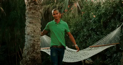 A man walks beside a hammock before the montage cuts to another man reclining on a lawn.