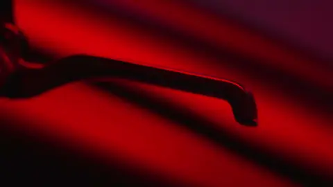Red-lit handle/detail frame has useful product mood but remains abstract.