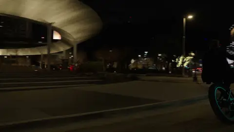 Wide night riding/location frame has useful city context but the bike subject is small and edge-cropped.